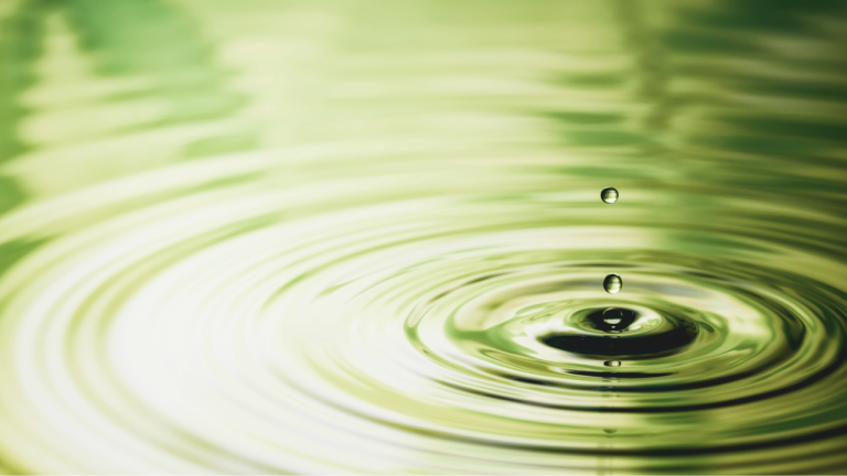 Water droplets dropping into a green-tinted pool, creating circular ripples. This image symbolizes the widespread, simplifying 'ripple effect' of the new EU CBAM Regulation 2025/2083 on global trade.